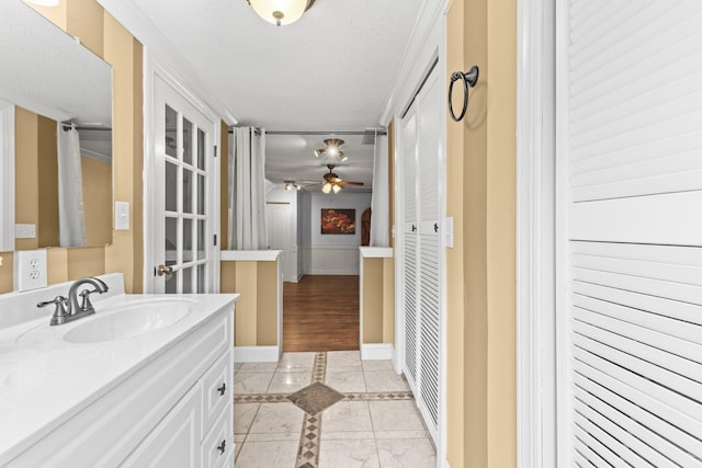 bathroom featuring ceiling fan, tile patterned flooring, vanity, and a textured ceiling