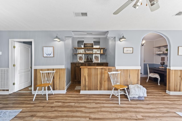 bar with ceiling fan, a textured ceiling, and hardwood / wood-style flooring