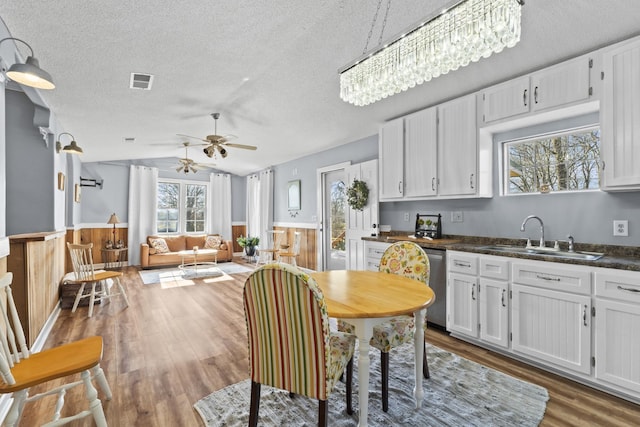 dining room with sink, vaulted ceiling, a textured ceiling, ceiling fan with notable chandelier, and hardwood / wood-style flooring