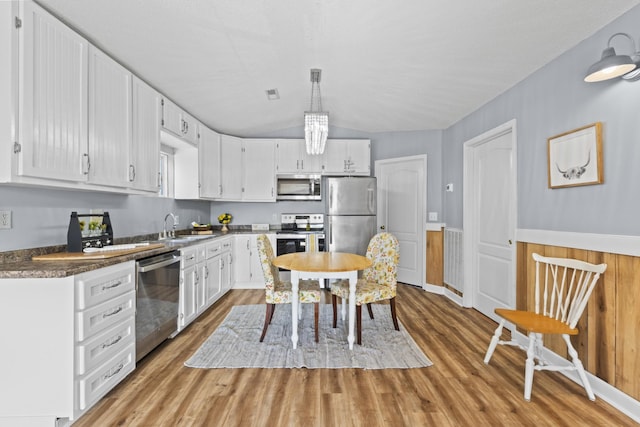 kitchen featuring white cabinetry, sink, decorative light fixtures, and appliances with stainless steel finishes