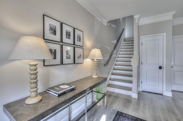 staircase with ornamental molding and hardwood / wood-style floors