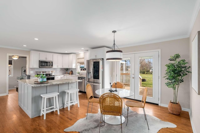 dining room with sink, french doors, light hardwood / wood-style flooring, and ornamental molding