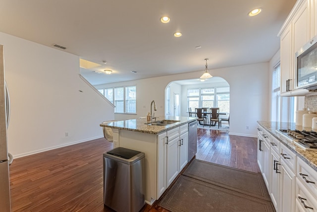 kitchen with sink, light stone countertops, an island with sink, appliances with stainless steel finishes, and white cabinetry