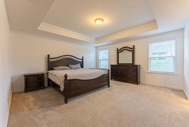 carpeted bedroom with a tray ceiling, multiple windows, and ornamental molding