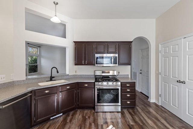 kitchen with sink, hanging light fixtures, dark hardwood / wood-style floors, dark brown cabinets, and appliances with stainless steel finishes