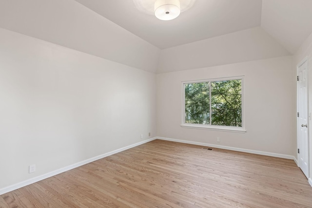 empty room with light hardwood / wood-style flooring and vaulted ceiling