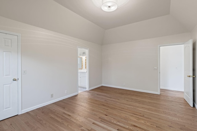 spare room featuring light hardwood / wood-style floors and vaulted ceiling