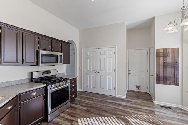 kitchen with dark hardwood / wood-style flooring, dark brown cabinets, stainless steel appliances, pendant lighting, and a notable chandelier