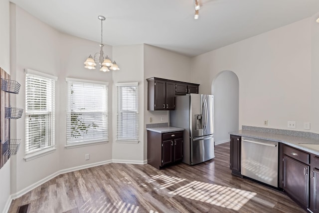 kitchen with hanging light fixtures, appliances with stainless steel finishes, dark brown cabinets, dark hardwood / wood-style flooring, and a chandelier