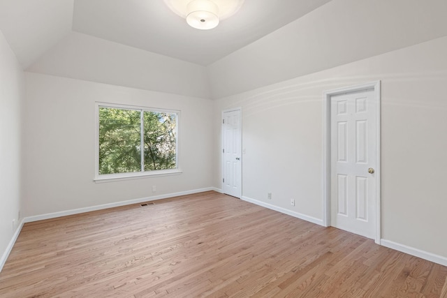 empty room with vaulted ceiling and light wood-type flooring