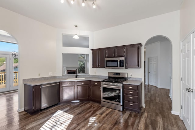 kitchen with dark wood-type flooring, sink, decorative light fixtures, dark brown cabinetry, and stainless steel appliances