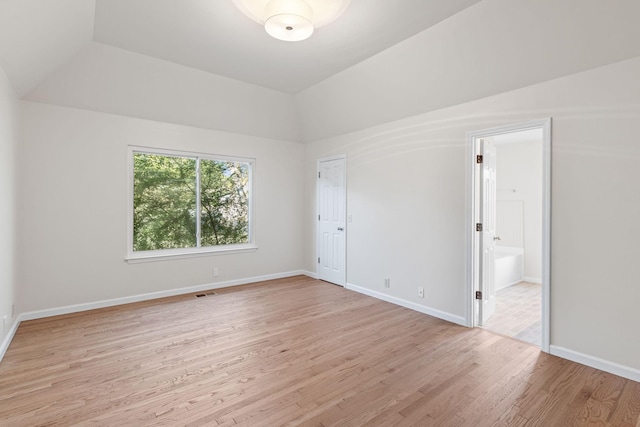 spare room featuring light hardwood / wood-style floors and vaulted ceiling