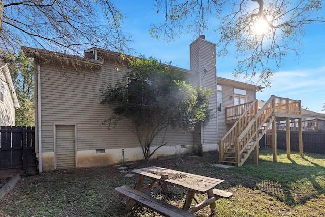 rear view of house with a wooden deck and a lawn