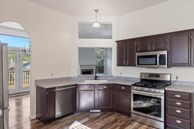 kitchen featuring appliances with stainless steel finishes, dark brown cabinets, pendant lighting, and sink