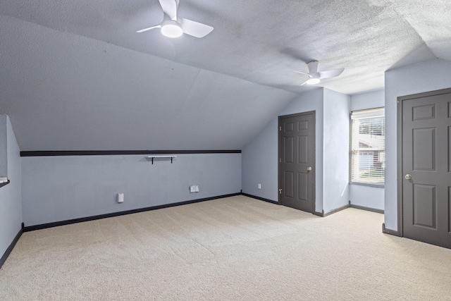 additional living space with a textured ceiling, ceiling fan, lofted ceiling, and light carpet