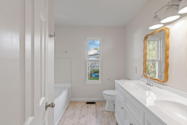 bathroom with vanity, a bathtub, toilet, and plenty of natural light