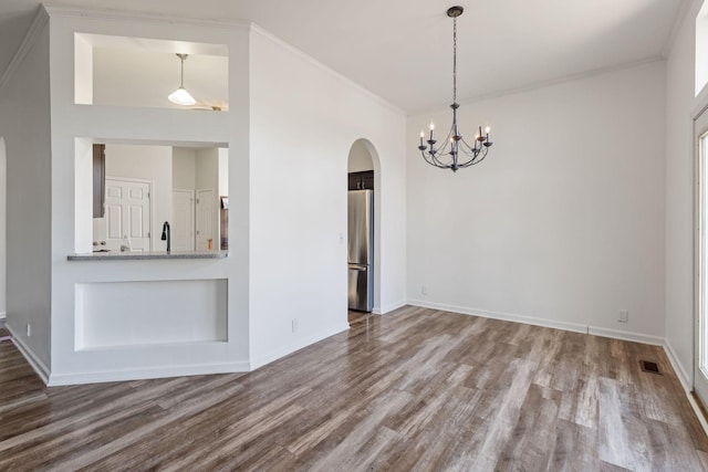 unfurnished dining area featuring a chandelier, wood-type flooring, and crown molding