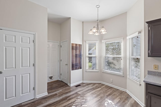 unfurnished dining area featuring hardwood / wood-style floors, a high ceiling, and a notable chandelier