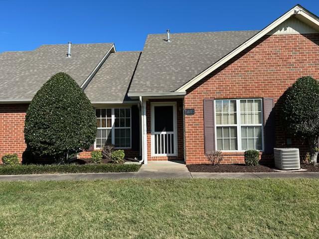 view of front of home with cooling unit and a front yard