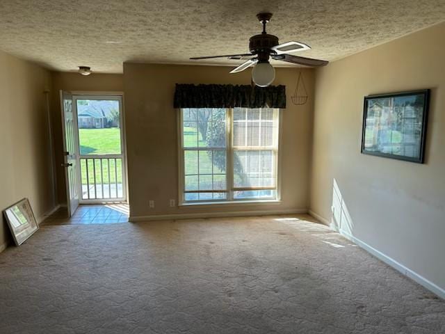 carpeted empty room with ceiling fan, plenty of natural light, and a textured ceiling