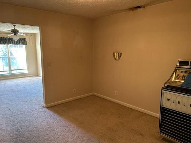 unfurnished room featuring a textured ceiling, ceiling fan, and light carpet