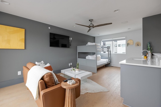 bedroom featuring light wood-type flooring, ceiling fan, and sink