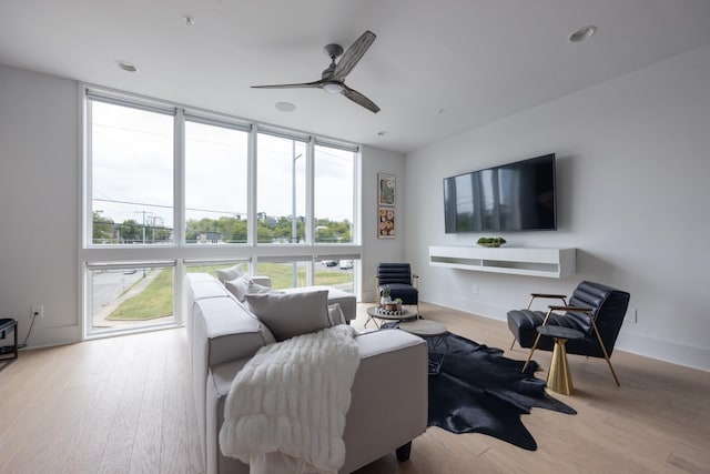 living room with ceiling fan, expansive windows, and light hardwood / wood-style floors