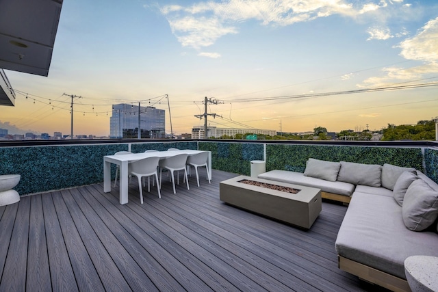 deck at dusk with an outdoor living space with a fire pit