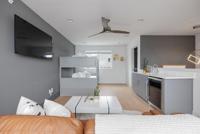 kitchen with gray cabinetry, ceiling fan, sink, wine cooler, and light wood-type flooring