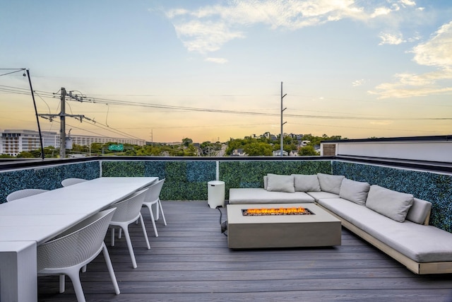 deck at dusk with an outdoor living space with a fire pit