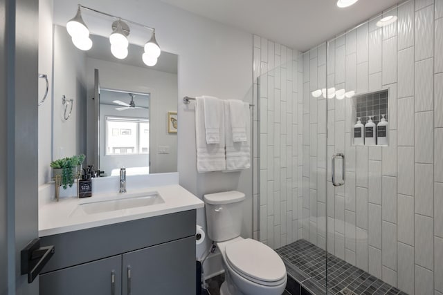 bathroom with ceiling fan, a shower with door, vanity, and toilet