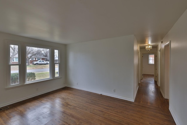 empty room featuring a notable chandelier and dark hardwood / wood-style floors