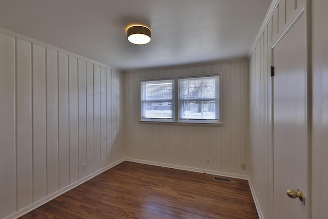 spare room with dark hardwood / wood-style floors, crown molding, and wooden walls