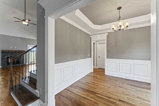 unfurnished room with ceiling fan with notable chandelier, hardwood / wood-style flooring, a raised ceiling, and ornamental molding