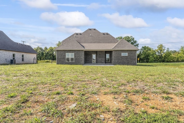 rear view of property with a lawn, central air condition unit, and a patio