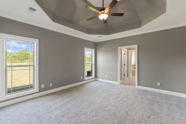 unfurnished room featuring a tray ceiling, ceiling fan, crown molding, and light colored carpet