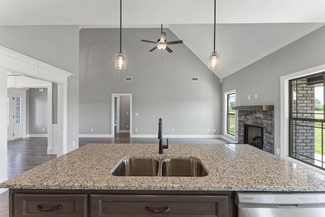 kitchen with dishwasher, a stone fireplace, light stone countertops, and sink