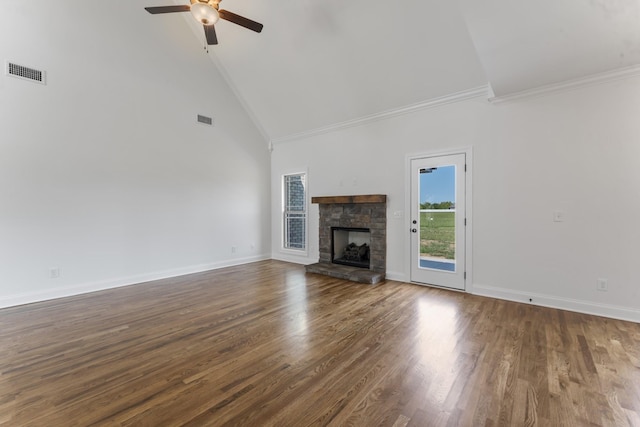 unfurnished living room with ceiling fan, dark wood-type flooring, a stone fireplace, high vaulted ceiling, and crown molding