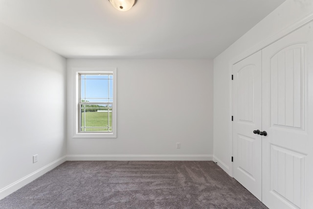 unfurnished bedroom featuring dark colored carpet and a closet