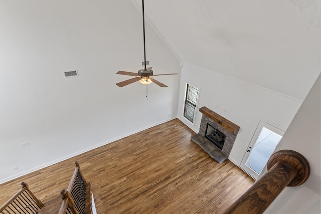 living room featuring hardwood / wood-style flooring, ceiling fan, and a stone fireplace