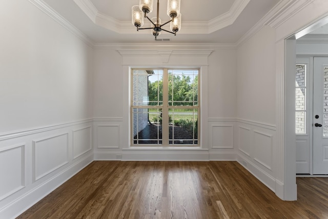 unfurnished dining area featuring a raised ceiling, ornamental molding, and a notable chandelier