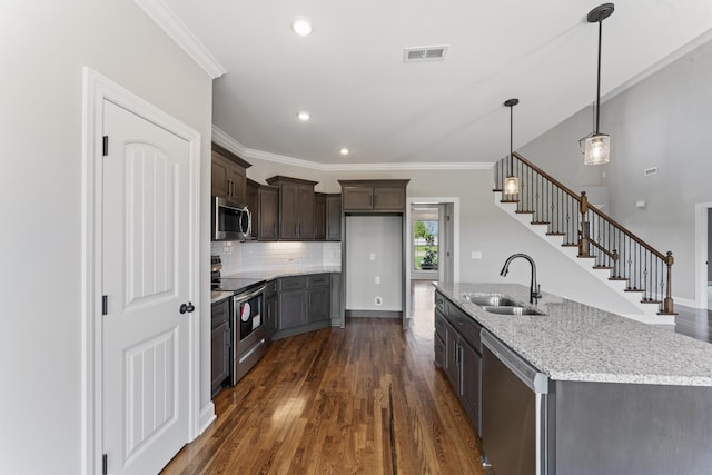 kitchen featuring sink, light stone countertops, decorative light fixtures, dark brown cabinetry, and stainless steel appliances