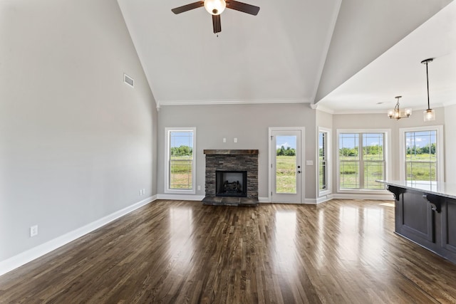 unfurnished living room featuring ceiling fan with notable chandelier, dark hardwood / wood-style floors, high vaulted ceiling, and a stone fireplace