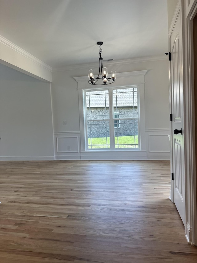 interior space featuring light wood-type flooring, ornamental molding, and a chandelier