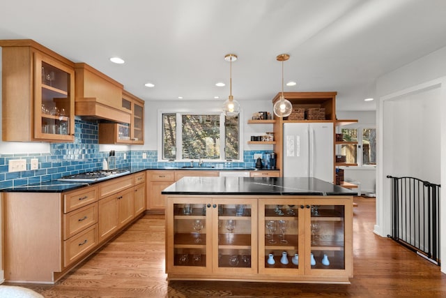 kitchen with a center island, sink, light hardwood / wood-style flooring, white fridge, and pendant lighting