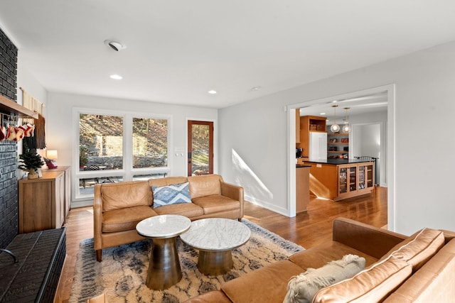 living room featuring light hardwood / wood-style floors and a brick fireplace