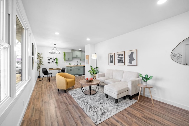 living room featuring wood-type flooring, sink, and an inviting chandelier