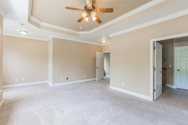 unfurnished room with ceiling fan, light colored carpet, crown molding, and a tray ceiling