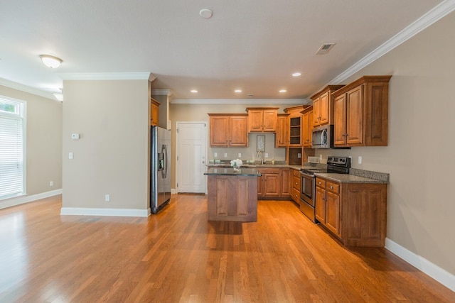 kitchen with sink, a center island, stainless steel appliances, crown molding, and light hardwood / wood-style floors