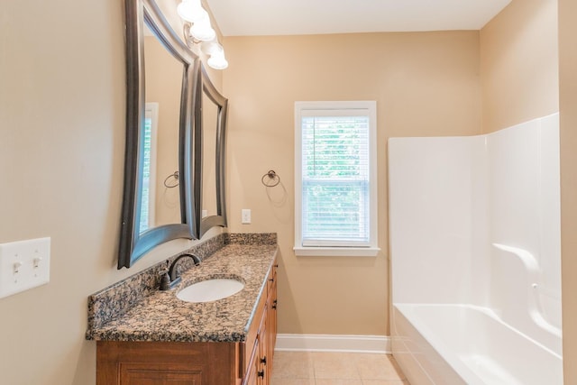 bathroom with tile patterned flooring, vanity, and tiled bath